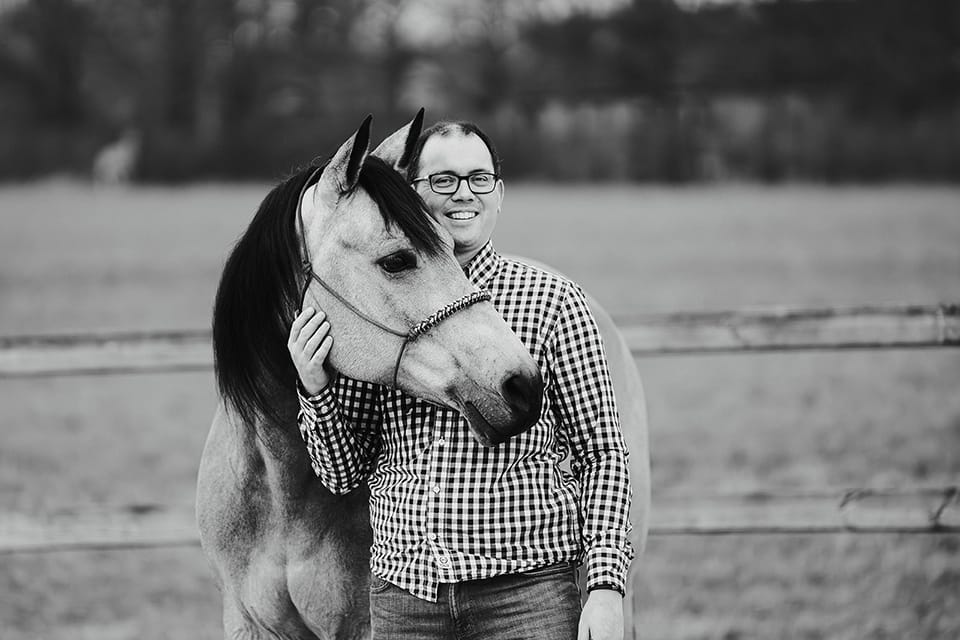 Black and white portrait of a man with his grey horse